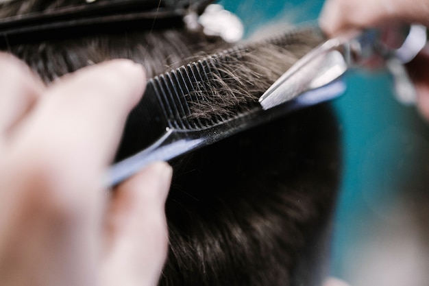 Barber cuts man's hair with scissors