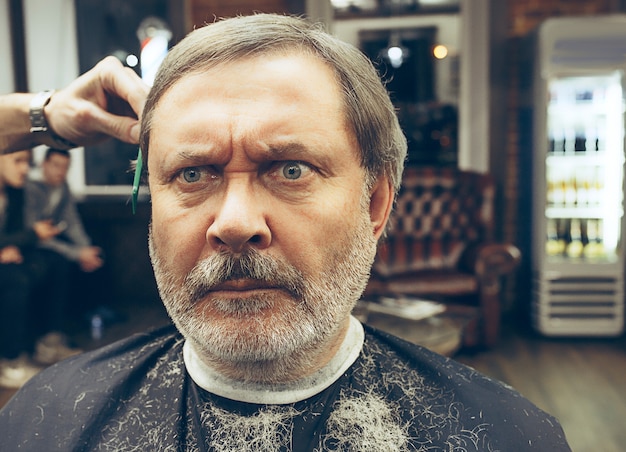 barber making haircut attractive old man in barbershop