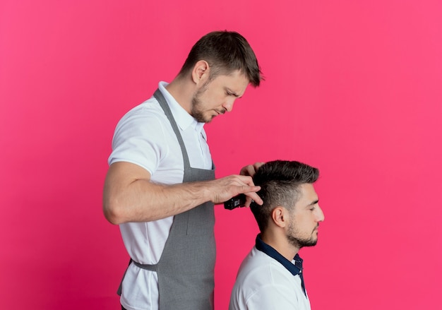 Free Photo | Barber man in apron cutting hair with hair cutting machine of satisfied client over pink wall Free Photo | Barber man in apron cutting hair with hair cutting machine of satisfied client over pink wall