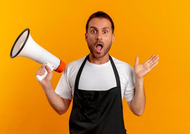Barber man in apron holding megaphone looking to the front confused and very anxious standing over orange wall