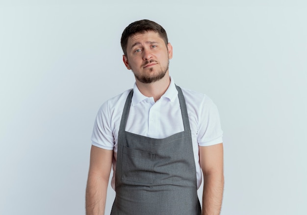 Barber man in apron looking at camera looking at camera with sad expression standing over white background
