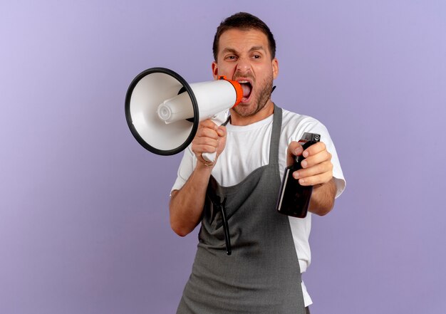 Barber man in apron shouting to megaphone with aggressive expression standing over purple wall