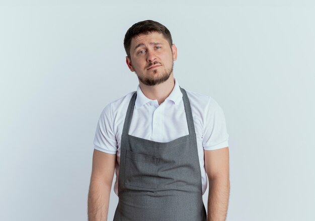 barber man in apron with sad expression standing over white wall