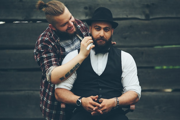 Парикмахер бреет бородатого мужчину в винтажной атмосфере