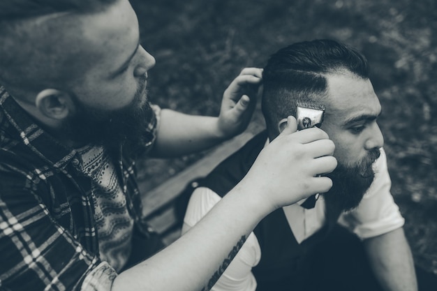 Barber shaves a bearded man in vintage atmosphere