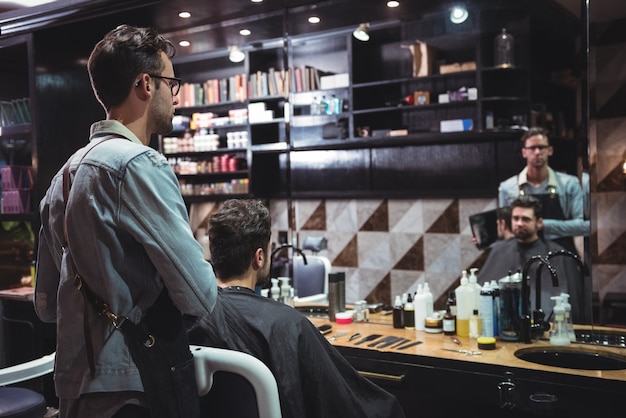 Foto gratuita barbiere che mostra all'uomo il suo taglio di capelli nello specchio