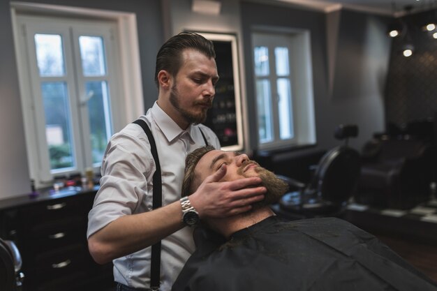 Barber styling beard of man