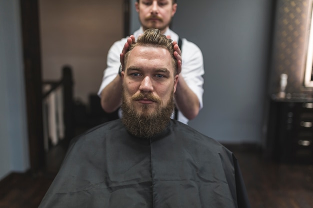 Barber styling hair of customer with mousse