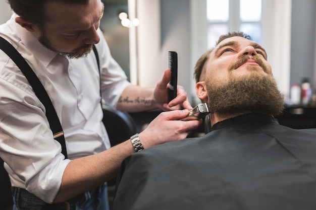 Free photo barber trimming beard of client