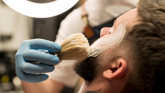シェービングクリームを使って男性客のひげを整える理容師