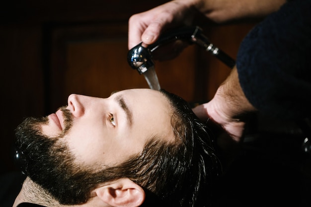 Barber washes hair of bearded man