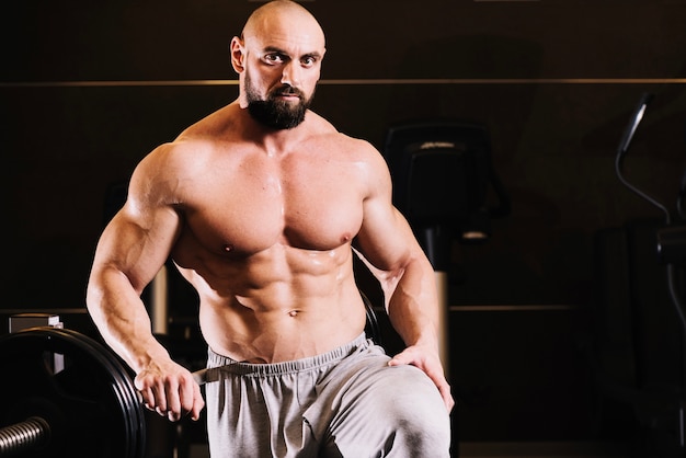 Bare-chested man posing near barbell