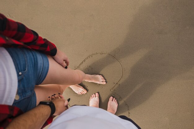 Bare feet couple holding hands on beach