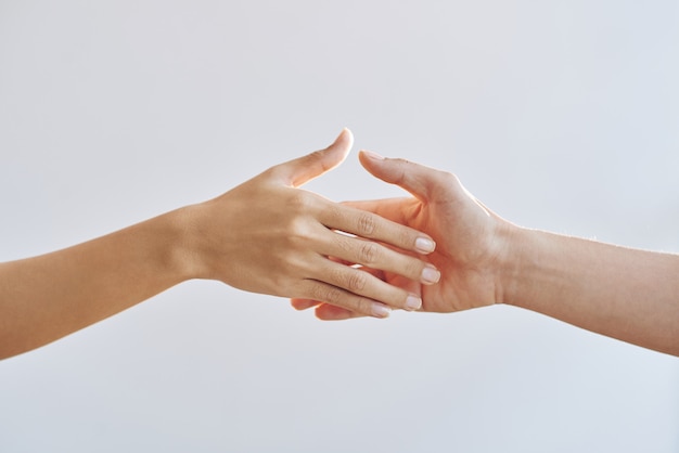 Bare hands of two unrecognizable people reaching towards each other