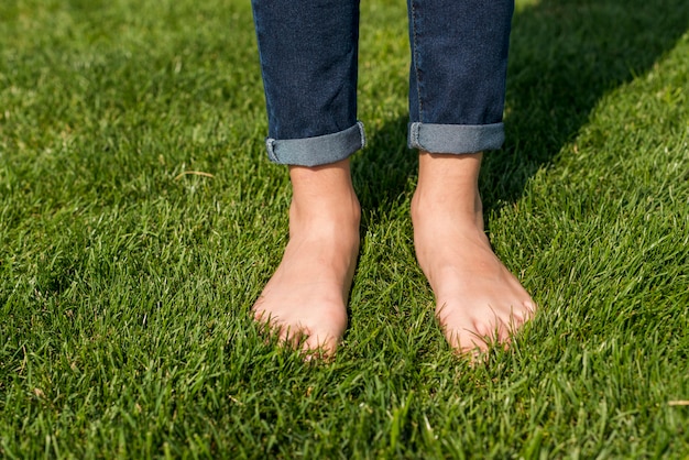 Босая маленькая девочка, стоя на траве крупным планом