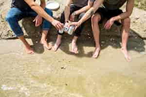 Foto gratuita amici maschi a piedi nudi che applaudono con birra