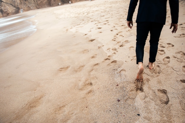 裸足の男が砂浜の上を歩いています。