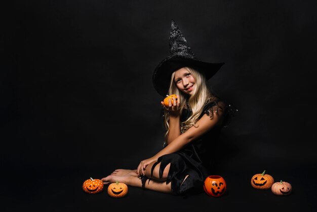Barefoot witch amidst jack-o-lanterns