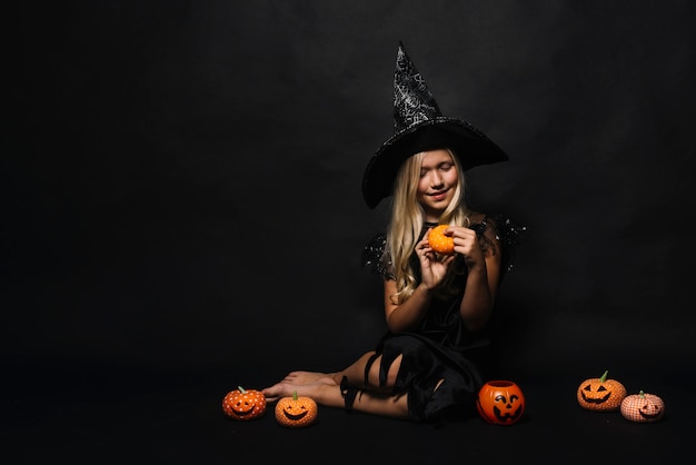 Barefoot witch looking at jack-o-lantern