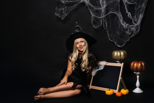 Barefoot witch near blackboard and Halloween decorations