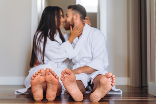 Barefoot woman and man sitting on floor at home