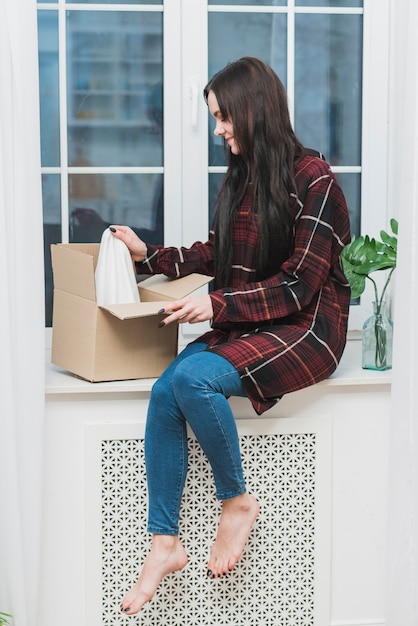 Free photo barefoot woman opening parcel