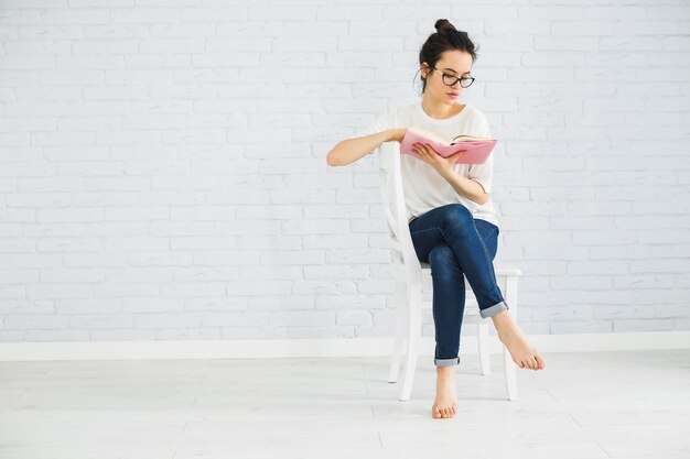 裸足の女性が椅子で読む