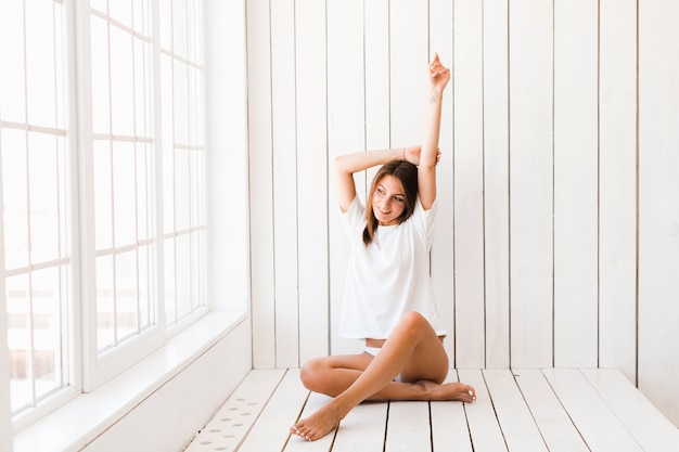 Barefoot woman stretching near window