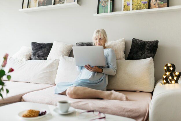 Barefoot woman using laptop on couch