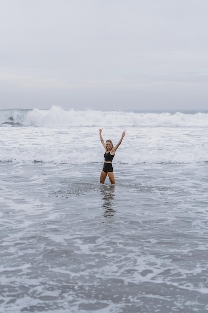Босоногая молодая женщина со стройным телом бежит по морскому прибою у бассейна, чтобы поддерживать себя в форме и сжигать жир. Фон пляжа с голубым небом. Женский фитнес, бег трусцой, спортивные занятия в летней семье