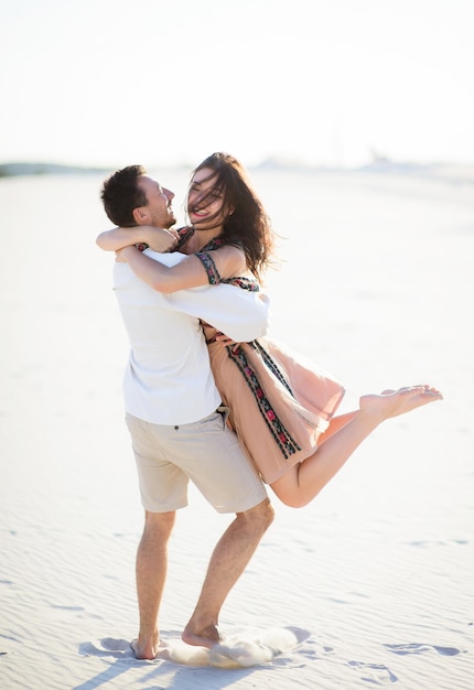 Barefooted couple in bright embroidered clothing walks on a white sand