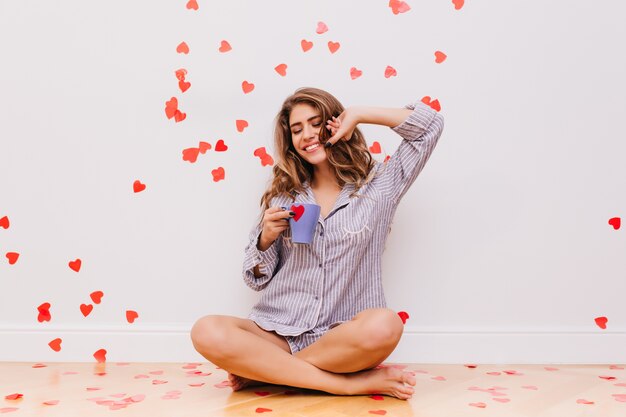 Barefooted pleasant woman sitting on the floor and drinking tea