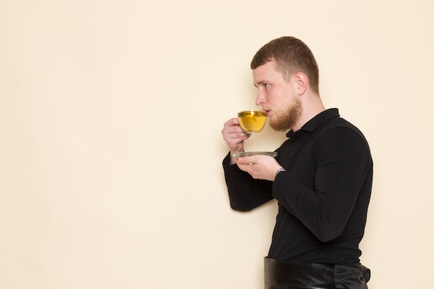 barista black suit drinking green hot tea on white floor