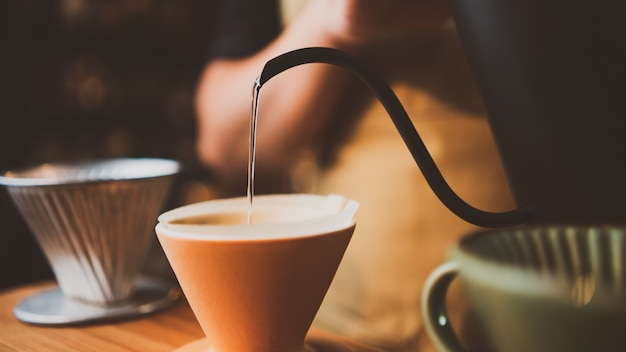 朝にコーヒーフィルターのドリップを醸造するバリスタ、新鮮な黒いエスプレッソの香りの飲み物、カフェのカップでの温かい飲み物、バーショップの背景での茶色のカフェイン Premium写真