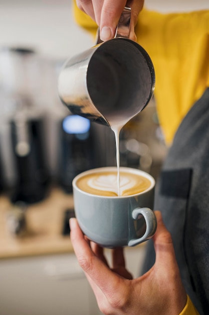 Barista decorating coffee cup with milk