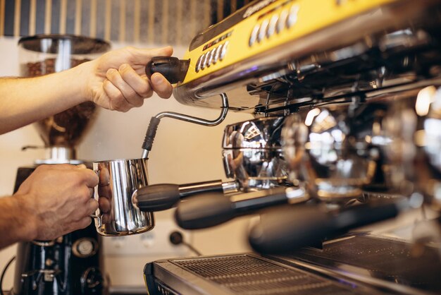 Barista heating up milk at a coffee machine