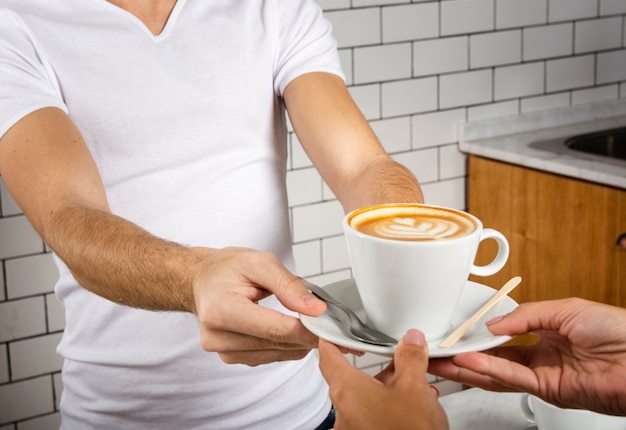 Barista offering a cup of coffee to a person