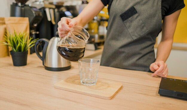 ガラスにコーヒーを注ぐバリスタ