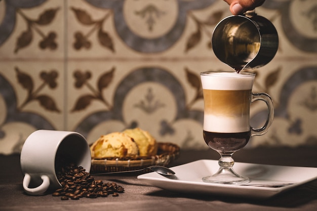 Free photo barista pouring the syrup into a layered latte