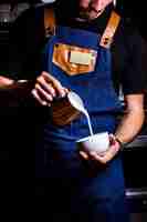 Free photo barista pours milk into the coffee