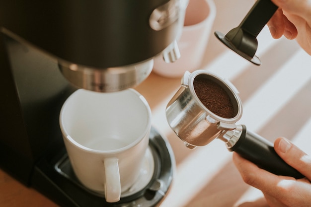 Barista pressing ground coffee in a filter coffee of machine