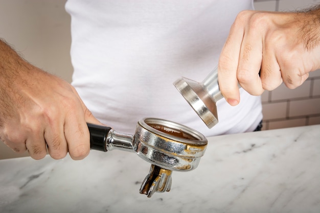 Barista pressing ground coffee using tamper