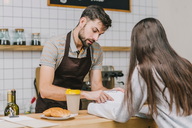 Barista showing prices to customer