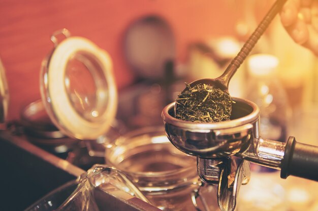 Barista taking dry green tea leaves to put into tea shot making machine