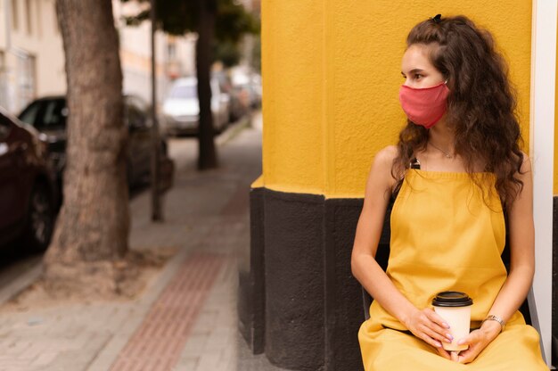 Free photo barista wearing a face mask while holding a cup of coffee with copy space