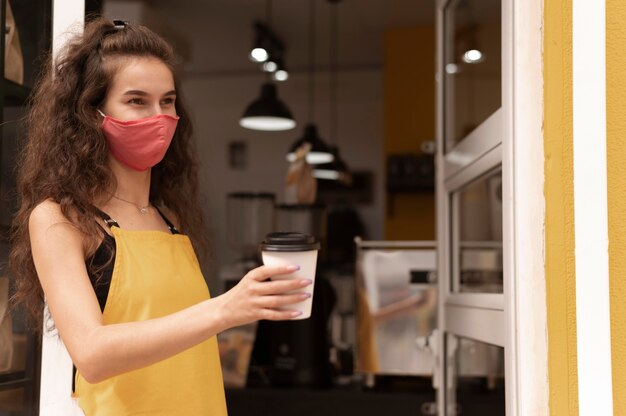 Foto gratuita barista che indossa una maschera per il viso con copia spazio