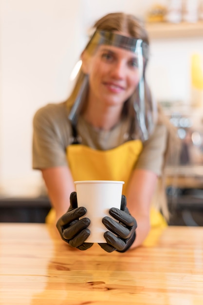 Barista wearing face protection serving coffee