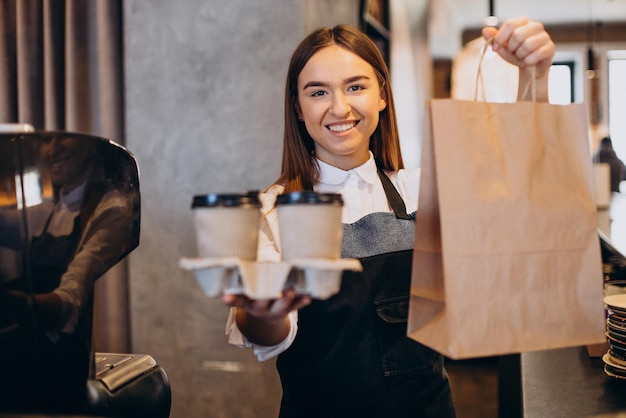 段ボールのカップでコーヒーを準備するコーヒーショップでバリスタの女性