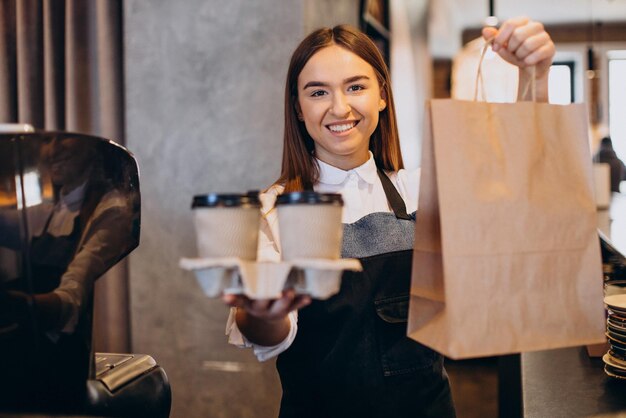 Barista woman at coffee shop preparing coffee in cardboard cups