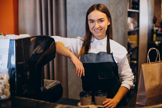 段ボールのカップでコーヒーを準備するコーヒーショップでバリスタの女性